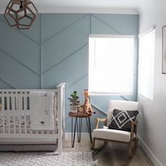 a baby's room painted in blue and white with a rocking chair, crib