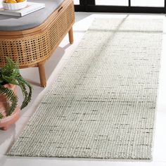 a white rug on the floor next to a chair and potted plant in front of a window