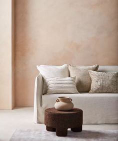 a white couch sitting next to a wooden table on top of a carpeted floor