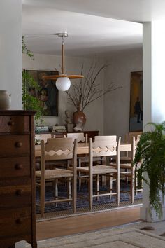 a dining room table and chairs in front of a mirror with plants on the wall