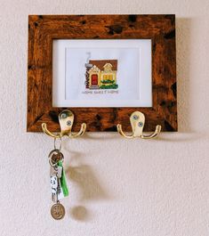 a wooden frame with two keys hanging from it's sides and a key holder attached to the wall