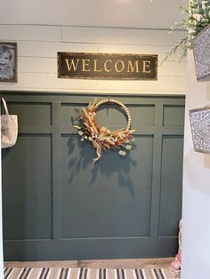 a welcome sign is hanging on the wall next to a door with a wreath in it