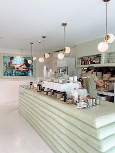 a man standing behind a counter with lots of cups on it in a room filled with lights