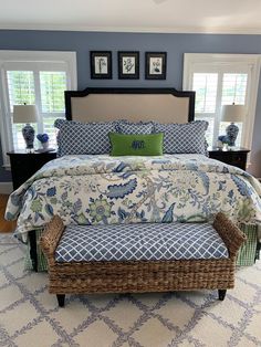 a bedroom with blue and white bedding, two windows, and a bench in front of the bed