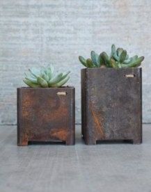 two metal planters with succulents in them sitting on a table next to each other