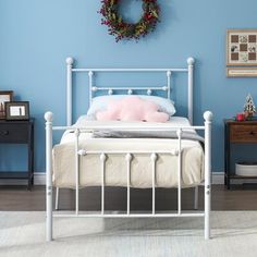 a bedroom with blue walls and white bedding has a wreath hanging on the wall