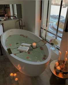 a large bathtub with candles on the floor next to it and a book in the tub