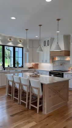 a large kitchen with white cabinets and an island in front of the stove top oven