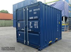 a large blue container sitting on top of a parking lot next to other containers and buildings