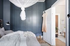 a bedroom with blue walls and white drapes hanging from the ceiling over the bed