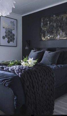 a bedroom with black walls and white flowers on the bed, along with two framed pictures