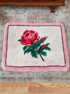 a pink rug with a rose on it is sitting on the floor next to a wooden bench