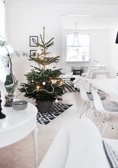 a living room with a christmas tree in the center and white chairs around it,