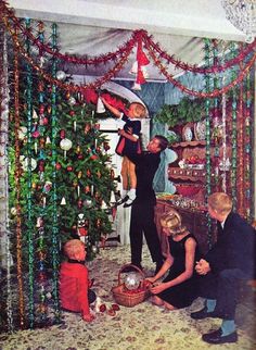 a group of people decorating a christmas tree in a room with garland and lights