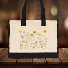 The Wildflower 100% Cotton Tote Bag. This Floral Tote Bag for Women features a captivating wildflower design that will add a splash of nature-inspired beauty to your daily routine. Measuring a generous 17” x 14” x 6”, this eco-friendly reusable bag is crafted from 100% cotton with reinforced stitching, ensuring both durability and elegance. It's roomy enough for beach days, picnics, errands, and everything in between, making it your new go-to bag for all your adventures. Reusable Canvas Bag In Natural Color, Natural Canvas Bag Reusable, Natural Bags With Reinforced Handles For Everyday Use, Reusable Canvas Bags In Natural Color, Natural Reusable Travel Bag, Black Bags For Spring Gifts, Black Bags For Spring Season Gifts, Reusable Bags For Spring, Reusable Shoulder Bag For Daily Use