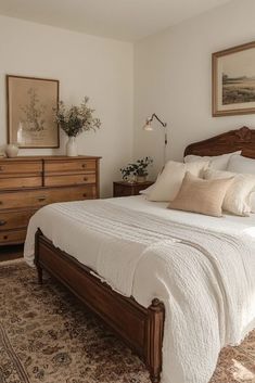 a bedroom with a bed, dressers and pictures on the wall