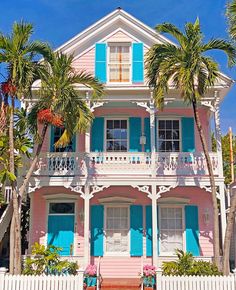 a pink house with blue shutters and palm trees