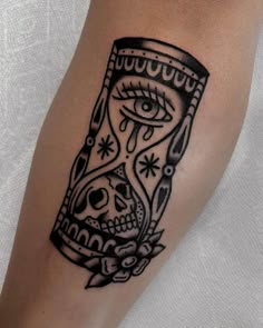 a black and white tattoo on the leg of a person with an hourglass in it