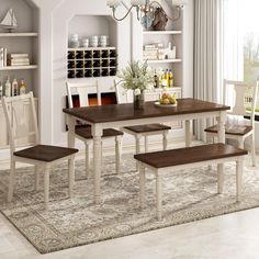 a dining room table with four chairs and a bench in front of the table is an area rug