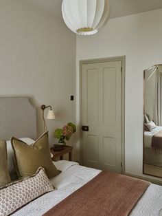 a bedroom with a bed, mirror and lamp