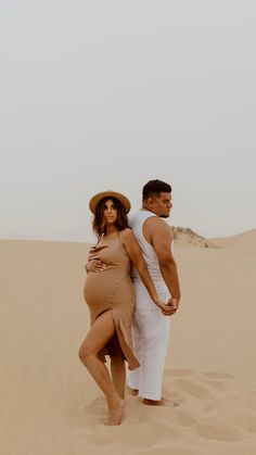 a pregnant couple standing in the desert