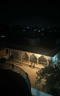 an empty courtyard at night with people sitting on benches