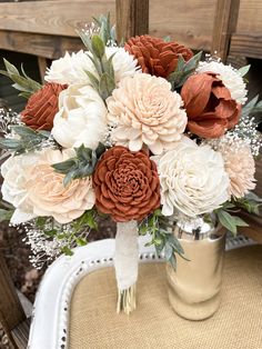 a vase filled with flowers sitting on top of a white and brown table cloth covered chair