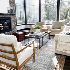 a living room with couches, chairs and a fire place in the middle of it