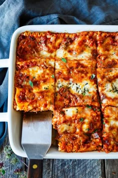 a white casserole dish filled with lasagna and cheese