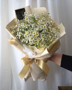 a person holding a bouquet of daisies in their hand