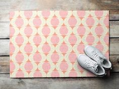 a pair of white sneakers sitting on top of a pink and beige mat with circles