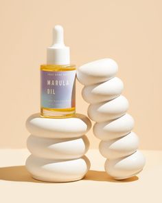 a bottle of marula oil sitting on top of a pile of white rocks next to it