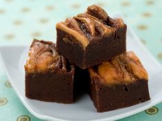 brownies with caramel drizzled on top sitting on a white plate