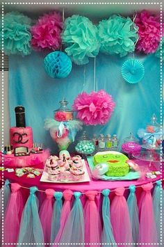 a pink and blue dessert table with cupcakes, cakes and other items on it