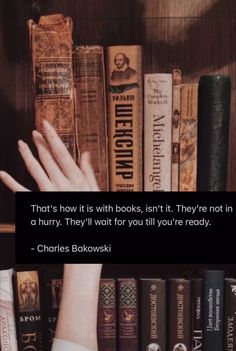 a person reaching for books in front of a book shelf with a quote on it