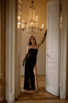 a woman in a black dress is standing by an open door