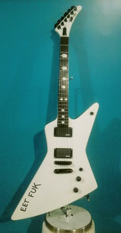 a white electric guitar sitting on top of a stand