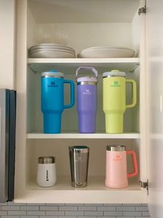 there are many cups and mugs in the cupboard