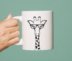 a hand holding a coffee mug with a giraffe drawn on it