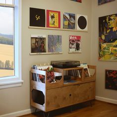 an entertainment center with various records on the wall and pictures on the wall behind it