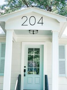 the front door of a white house with blue shutters and numbers on it's side