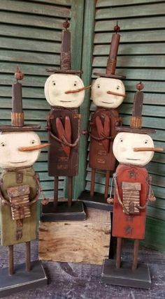 three wooden toy soldiers standing next to each other on top of a floor in front of a building