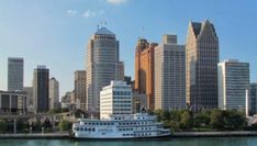 a large white boat floating on top of a river next to tall buildings in a city