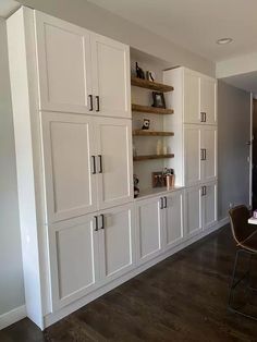 an empty room with white cabinets and chairs on the floor in front of a large window