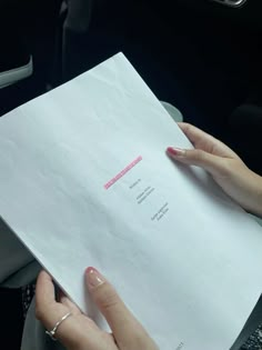 a woman is holding a piece of paper in her hand while sitting in the car