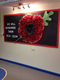 a red flower is placed in front of a black sign that says we will remember them