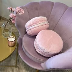 two round pillows sitting on top of a purple chair next to a vase with flowers