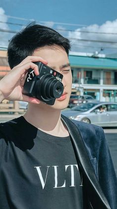 a young man holding up a camera to his face