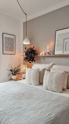 a white bed sitting in a bedroom next to two framed pictures on the wall above it