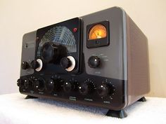 an old fashioned radio sitting on top of a white cloth covered table next to a wall